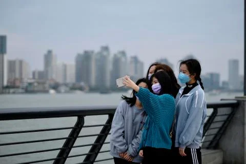During coronavirus, young girls in surgical mask take selfie at the bund Stock Photos