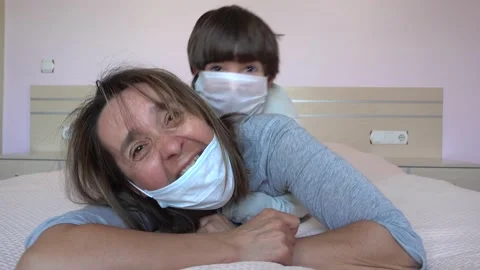 During Covid-19 lockdown Child in mask attacks his resting on bed mother Stock Footage 131358374