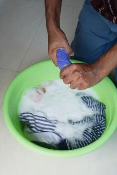 During the daytime, laundry is being washed in a green basin Stock Photos