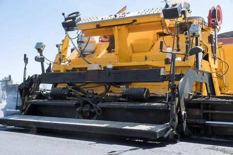 During highway construction, a pavement machine lays fresh bitumen asphalt over Stock-Fotos