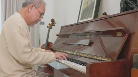 During his relaxation, an elderly Asian man plays the piano. On weekends, do som Stock Footage 215721838