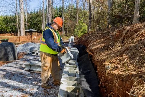 During installation of concrete block retaining wall, contractor mounted a Stock Photos