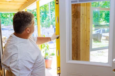 During installation of new front door, a carpenter uses yellow spirit measure Stock Photos