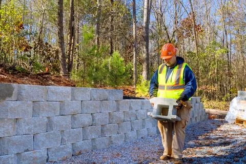 During installation of retaining wall, a contractor mounted concrete blocks Stockfoto's