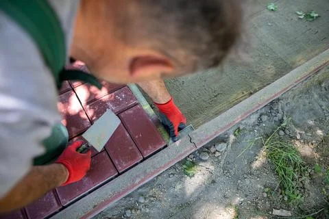During the laying of paving blocks, the worker checks with a protractor, the Foto stock