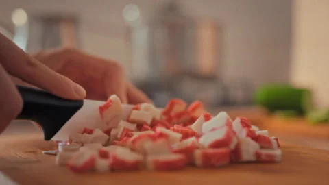 During meal preparation in home kitchen chef-woman slices bright crab sticks Stock Footage 346391830
