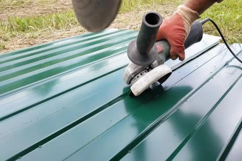 During the roofing work, a construction worker sprays a steel sheet with a tr 스톡 사진