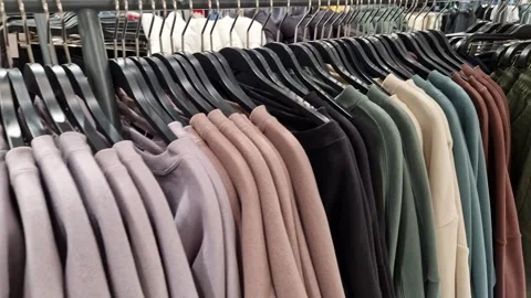 During shopping trip, man selects a sweater on hangers in store. Dive into Stock Footage 265999352