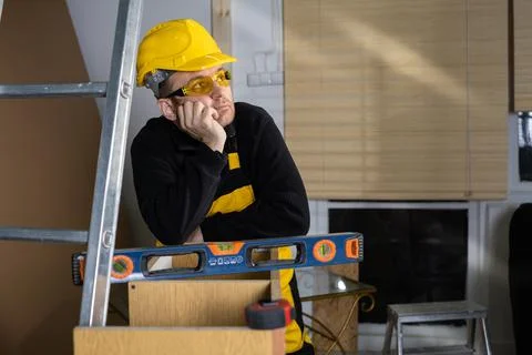 During a short break, the construction worker puts his hand under his chin and Foto stock