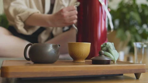 During a tea ceremony at a table indoors, a person reaches for a clay teapot Stock Footage 348189354