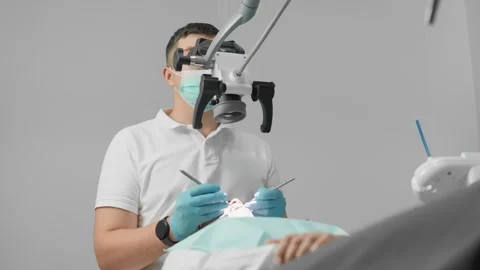 During the tooth extraction procedure, the doctor uses a microscope to precisely Stock Footage 272646438