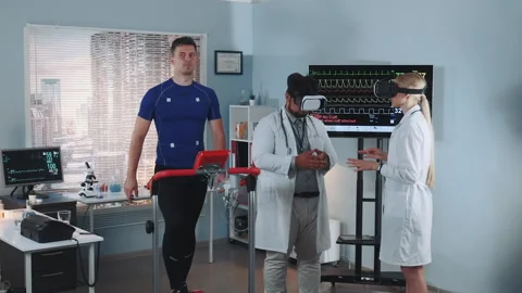 During the treadmill test two mixed race doctors in VR glasses speaking about Stock Footage 153480286
