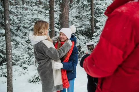 During a walk through the winter forest, a father takes photos of a mother and Stock Photos