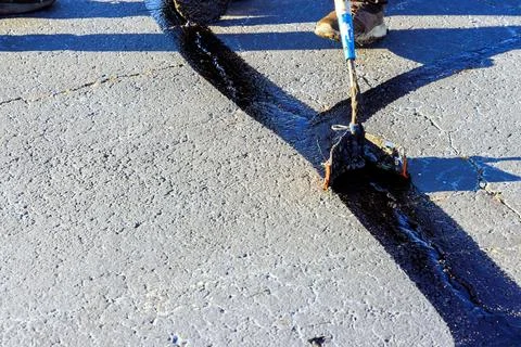 During worker patcher performs coated filling asphalt cracks sealing bitumen 写真素材