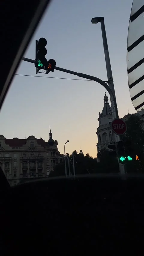 Dusk city drive with changing traffic lights and silhouetted historic skyline 库存影片 341662722