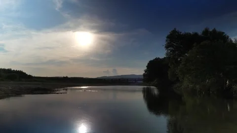 Dusk, the river and an old bridge with the setting sun reflecting off it. Stock Footage 279121955