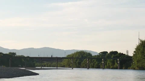 Dusk, the river and an old bridge with the setting sun reflecting off it. Stock Footage 279122739