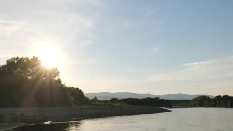 Dusk, the river and an old bridge with the setting sun reflecting off it. Stock Footage 279122743