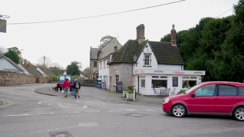 Dusk scene on the main road in Cheddar, cars driving past illuminated shop Vídeo Stock 331229593