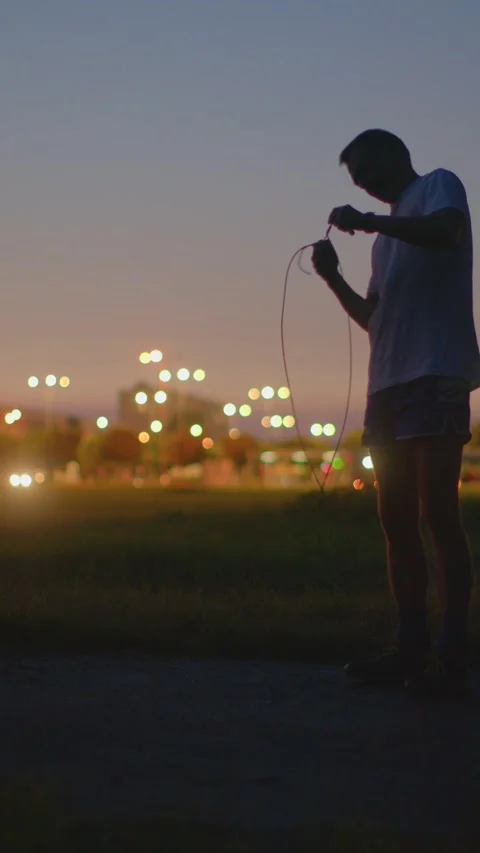 Dusk setting as man performs warmup stretches prior to jump rope session Stock Footage 324591483