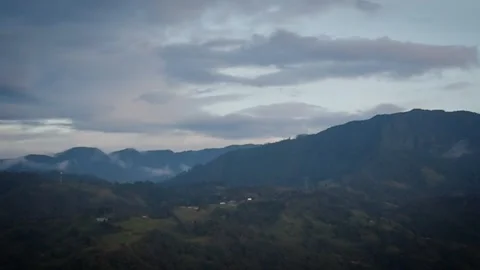 Dusky Valley Lights Twinkling Below Imposing Summits and Gray Vapors Stock Footage 316797630