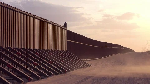 Dust blows at sunset at the border wall at the US Mexico border near Imperial Stock Footage 79401682