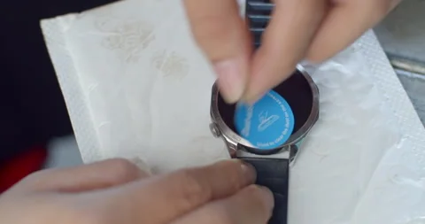 Dust is carefully removed from a smartwatch screen before applying a protective  Stock Footage 323344015