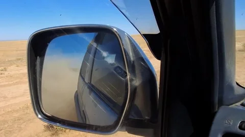 Dust cloud rising behind an off-road car reflected in a side mirror Stock Footage 345155588