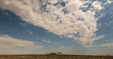 Dust devil blows by Mojave Desert as fluffy white clouds drift in sky, Stock Footage 115731615