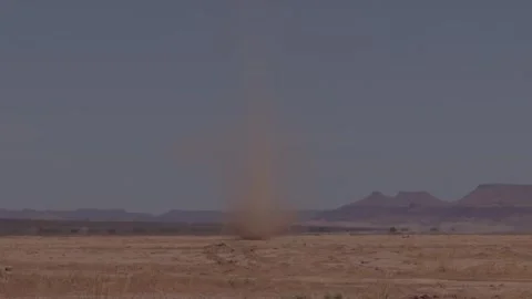 Dust devil whirlwind rising above flat arid desert plain with distant mesa Stock Footage 335962492