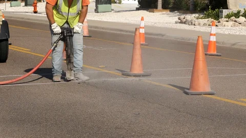 Dust flies from the machine as a man laborer works with a jackhammer. Stock Footage 127936114