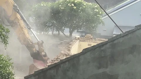 Dust from a house being knocked down by a large industrial digger 4K Stock Footage 327049340