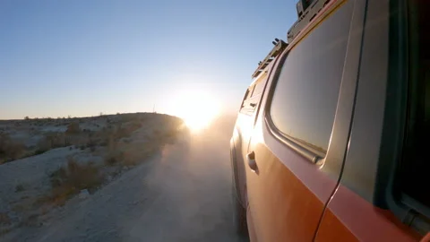 Dust kicking up while driving on dirt road looking towards the sun Stock Footage 143681790