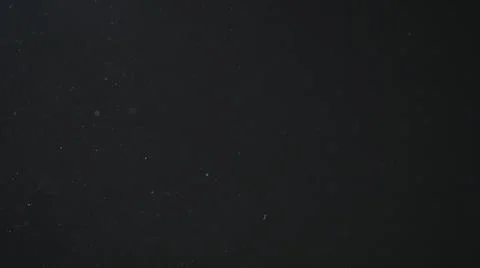 Dust particles float in cool light on black background Stock Photos