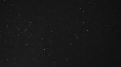 Dust particles float in neutral light on black background Stock Photos