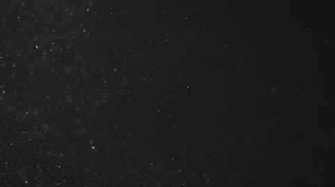 Dust particles float in neutral light on black background Stock Photos