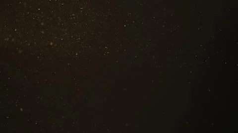 Dust particles float in sunlight on black background Stock Photos
