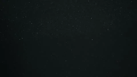 Dust particles float in sunlight on black background Stock Photos