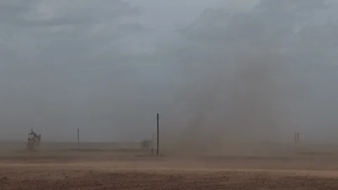 Dust storm over an empty field near oil pump jack, 4K. Stock Footage 101739230
