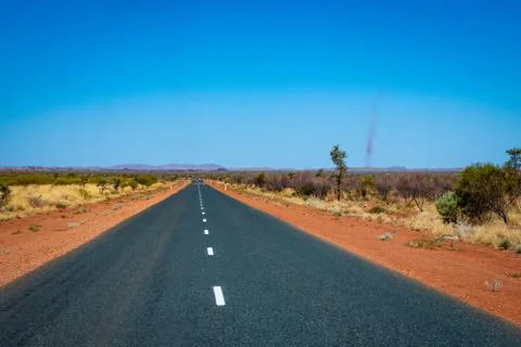 Dust storms besides dark road leading through red sanded Australian landscape Foto stock