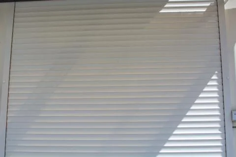 Dusted white wall shutter roller door with diagonal shadow Stock Photos