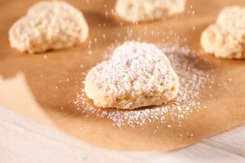 Dusting heart-shaped biscuits with icing sugar Stock Photos
