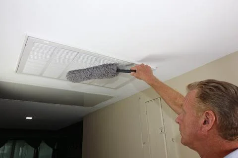 Dusting HVAC Intake Vent Grid By Adult Man to Reduce Allergens Stock Photos