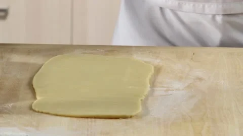 Dusting a worksurface with flour and rolling out dark shortbread dough Stock Footage 24663253
