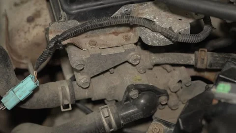 A dusty car engine compartment showing a thermostat housing and hoses. Stock Footage 342261954