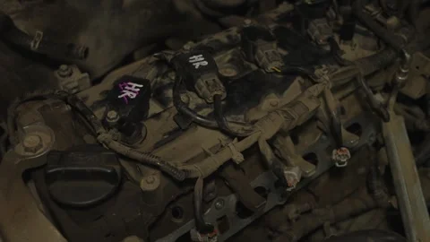 A dusty car engine valve cover with ignition coils and connected wiring harn Stock Footage 340558677