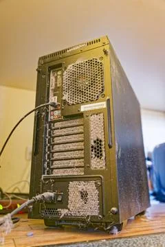 Dusty computer tower with clogged ventilation and cables on wooden floor Stock Photos