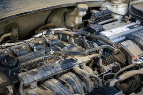 Dusty engine compartment of a used car with battery hoses and wiring. Vehicle Foto stock