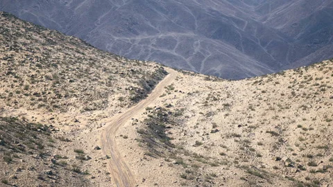 Dusty road winding through arid mountains in a remote desert landscape Video stock 331417758