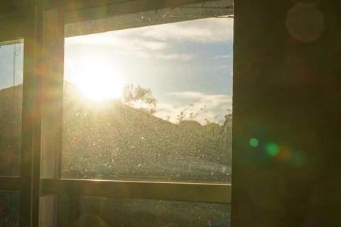 Dusty window with sunlight shining through dirty glass in hazy room. Stock Photos